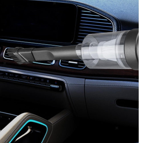 Person using a handheld car vacuum cleaner to easily clean dirt from under car seats.